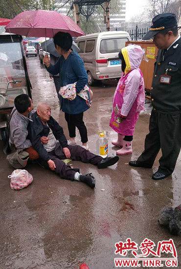 女孩為倒地老人撐傘。