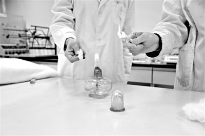 實(shí)驗(yàn)人員操作的燃燒檢測(cè)法中，真蠶絲離開(kāi)火焰就熄滅(左)。