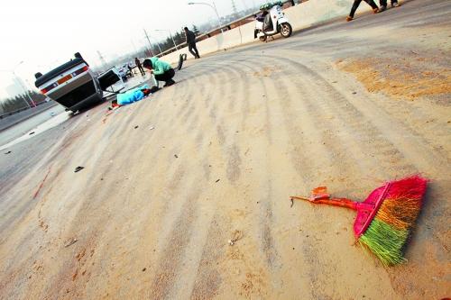 被撞的環(huán)衛(wèi)工躺在地上，身上蓋著藍(lán)色布塊，現(xiàn)場除散落的汽車碎片外，還留有被撞斷的掃帚。