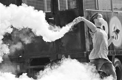 12月2日，泰國(guó)曼谷，一名反政府示威者在總理府附近向負(fù)責(zé)執(zhí)勤的警察投擲催淚彈。英拉請(qǐng)求示威者不要再試圖占領(lǐng)政府工作部門(mén)，不要逼迫政府工作人員選邊站。