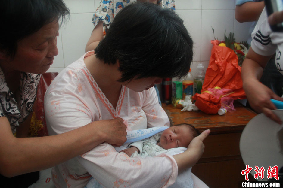 圖為久別重逢，獲救嬰兒母親悉心撫摸愛(ài)子。張一辰 攝