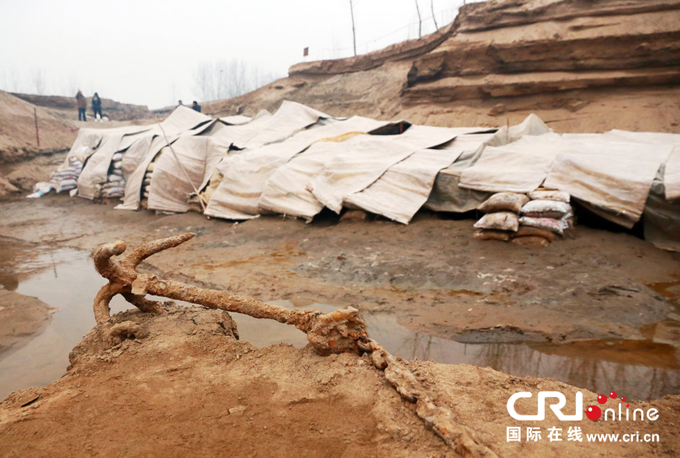 2014年1月6日，河南洛陽古沉船發(fā)掘現(xiàn)場，古沉船鐵錨從見天日，靜靜地躺在古船旁。