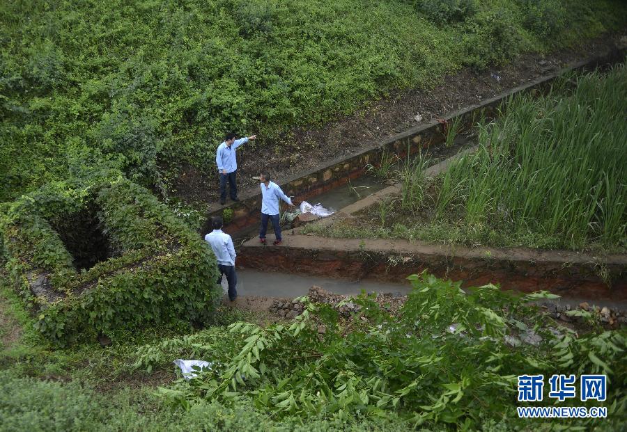 5月18日，工作人員在槽罐車泄漏現(xiàn)場附近的水渠邊查看情況。