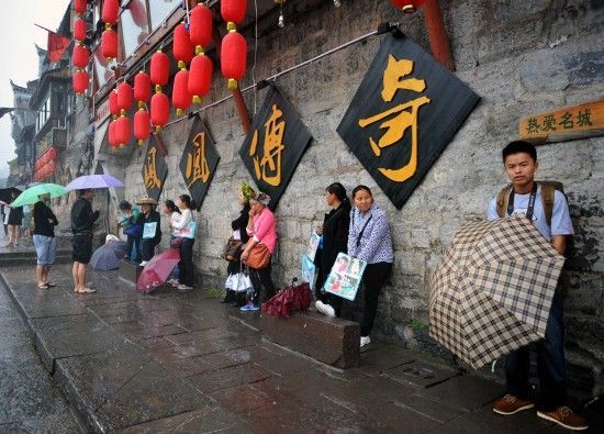 　4月29日上午11時(shí)20分，一些游客和古城當(dāng)?shù)氐木用穸阍谝粋€(gè)酒吧的屋檐下避雨。這些當(dāng)?shù)鼐用褚詾橛慰团恼罩\生，一場(chǎng)降雨讓他們的生意更加清淡。