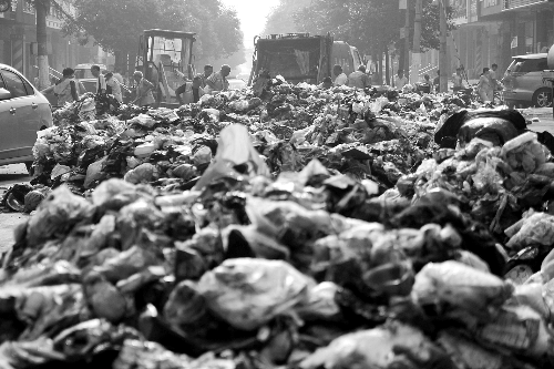 垃圾堆滿整個路口，環(huán)衛(wèi)工人們正在清理