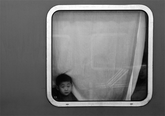 一個(gè)孩子把頭伸向窗外，他想再看送別的親人一眼