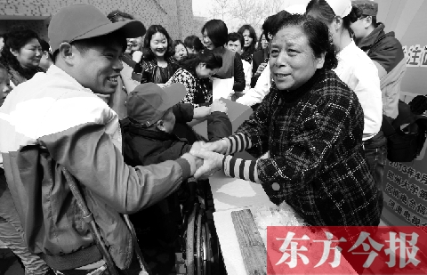 昨日，鄭大四附院的大樓前，“面人鄭”鄭玉芬（右）向前來捐款的殘疾人表示感謝