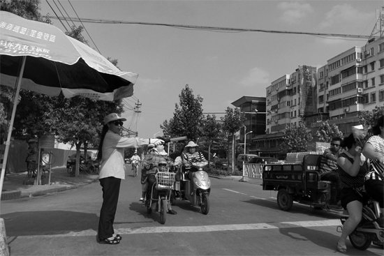 昨日，開封市區(qū)一名協(xié)管員在指揮群眾過馬路