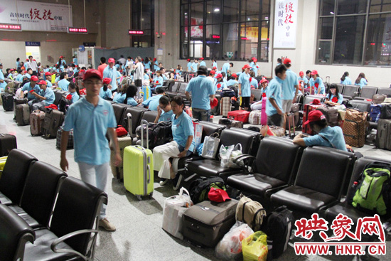 大學(xué)生志愿者在火車站候車室內(nèi)整裝待發(fā)。