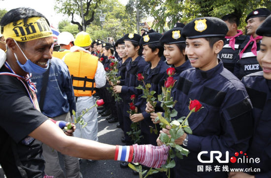 2013年12月03日,曼谷總理府與曼谷警署允許反政府示威民眾進入,雙方進入暫時“停戰(zhàn)”狀態(tài)迎接泰王生日。曼谷警察總署,女警們手持鮮花送給反政府示威民眾。圖片來源:Manish Swarup/東方IC
