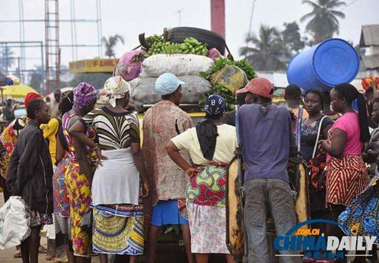 當(dāng)?shù)貢r(shí)間2014年8月14日，利比里亞蒙羅維亞，市場(chǎng)里的商人們圍著一輛汽車。