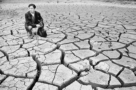 蹲在干涸的田地里，焦裕祿為饑餓的百姓揪心不已 《焦裕祿》劇照